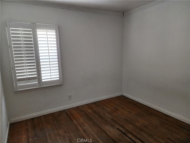 empty room featuring crown molding, baseboards, and wood finished floors