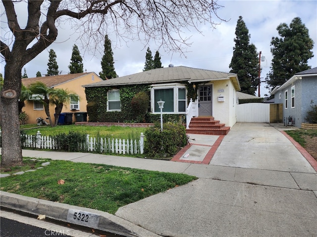 view of front facade featuring stucco siding, driveway, and fence