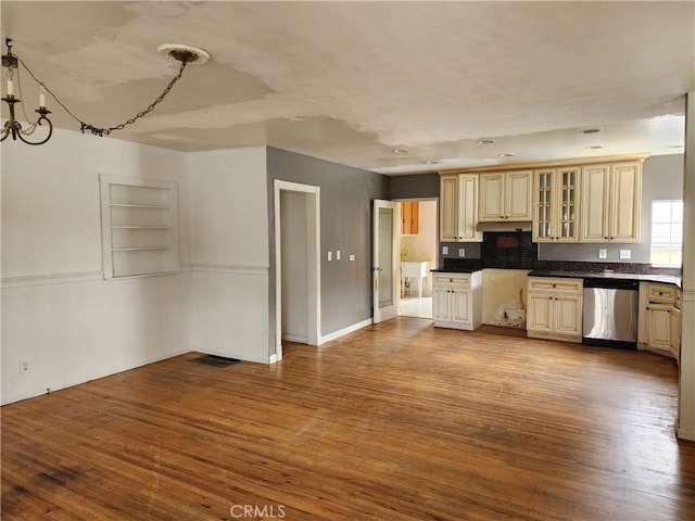 kitchen featuring glass insert cabinets, stainless steel dishwasher, visible vents, and wood finished floors