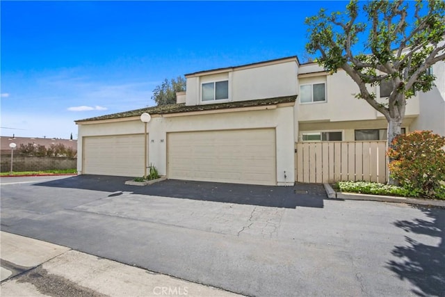 multi unit property featuring stucco siding, driveway, and a garage