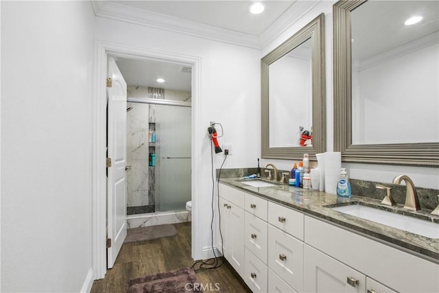 bathroom with a shower stall, ornamental molding, wood finished floors, and a sink