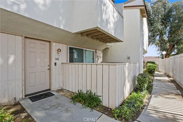 entrance to property with stucco siding and fence