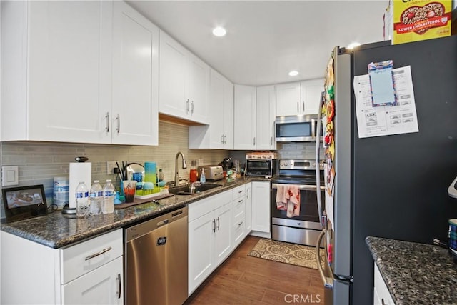 kitchen featuring a sink, dark wood finished floors, white cabinetry, appliances with stainless steel finishes, and decorative backsplash