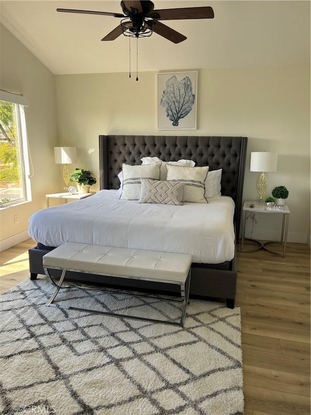 bedroom featuring a ceiling fan, lofted ceiling, wood finished floors, and baseboards