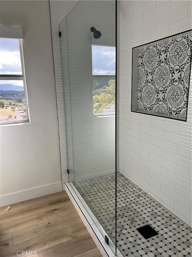 bathroom featuring wood finished floors, a walk in shower, and baseboards