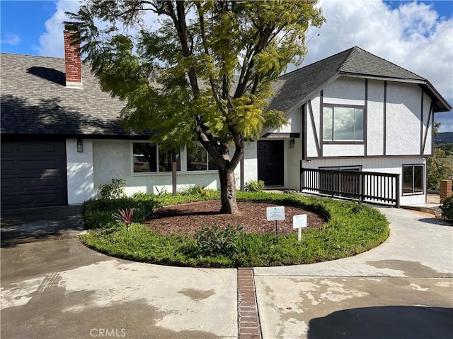 english style home with a chimney, stucco siding, and a shingled roof