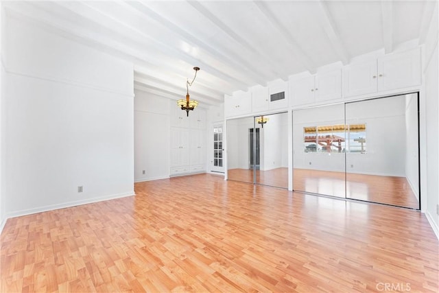 unfurnished living room featuring light wood finished floors, beamed ceiling, a chandelier, and baseboards