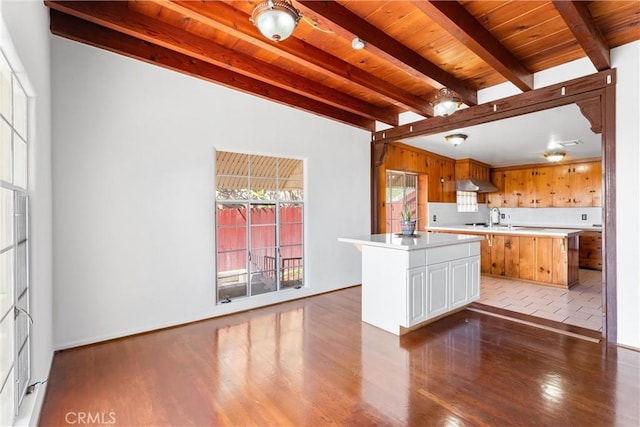 kitchen with beamed ceiling, wood finished floors, range hood, wooden ceiling, and light countertops