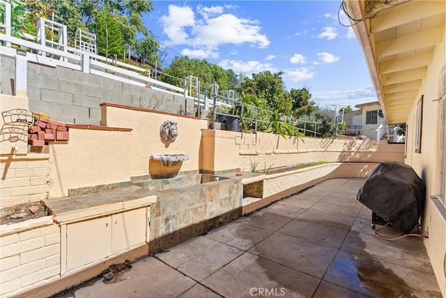 view of patio with area for grilling and fence