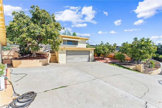 exterior space featuring stairway, fence, stucco siding, concrete driveway, and a garage