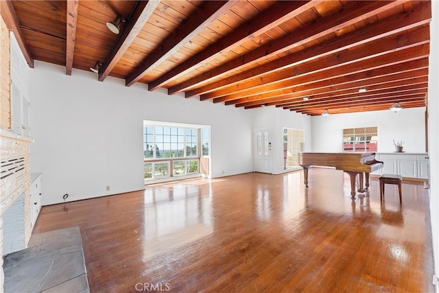 unfurnished living room with beam ceiling, a stone fireplace, wood ceiling, and wood finished floors