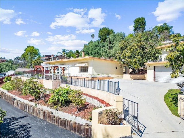 view of front of house featuring a fenced front yard, a garage, driveway, and stucco siding