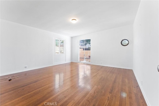 spare room featuring baseboards and wood finished floors