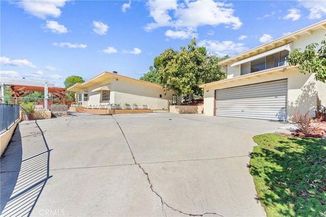 view of front of property with fence, a garage, and stucco siding