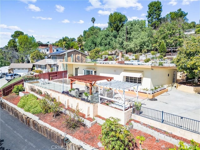 rear view of property featuring fence, a pergola, and stucco siding