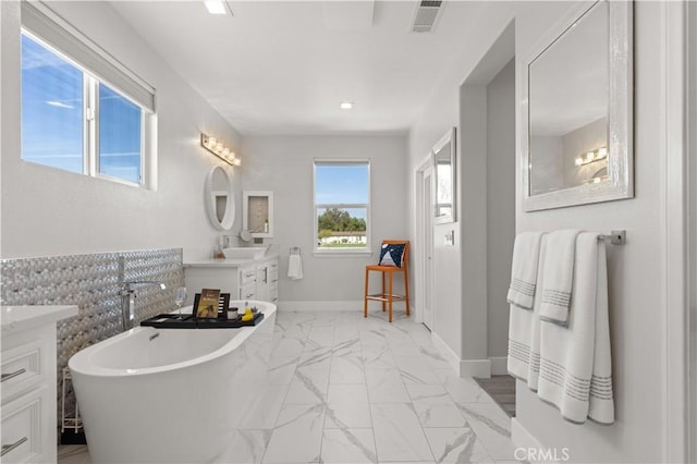 bathroom featuring visible vents, marble finish floor, baseboards, a freestanding bath, and vanity