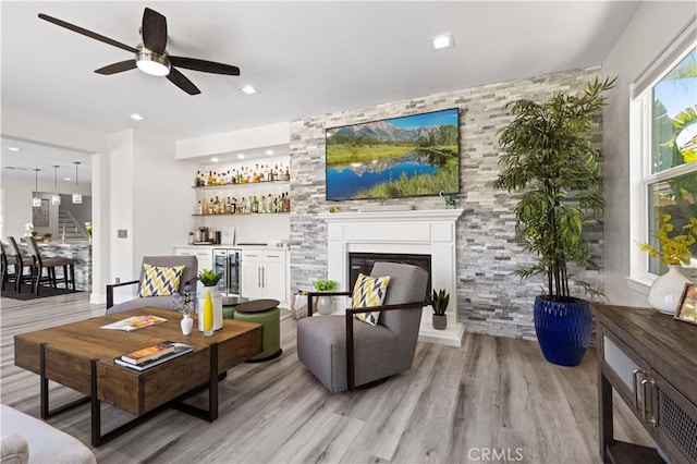 living area featuring wine cooler, a dry bar, a ceiling fan, and light wood finished floors