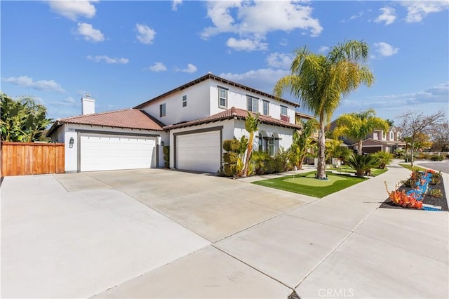 view of front of home featuring stucco siding, a tile roof, fence, concrete driveway, and an attached garage