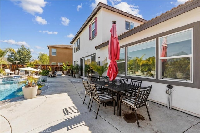 view of patio with outdoor dining space, a fenced in pool, and fence