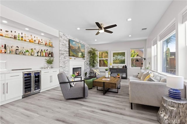 living room with beverage cooler, recessed lighting, light wood-style floors, bar, and ceiling fan