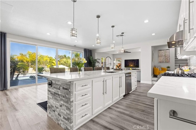 kitchen with white cabinets, light wood-type flooring, open floor plan, and a sink