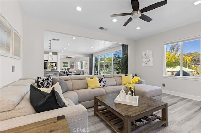 living room featuring visible vents, plenty of natural light, light wood-style flooring, and ceiling fan