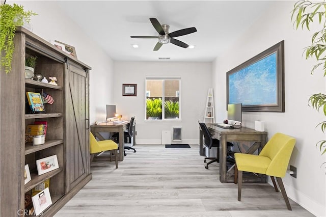 office space with visible vents, ceiling fan, baseboards, and light wood-style floors