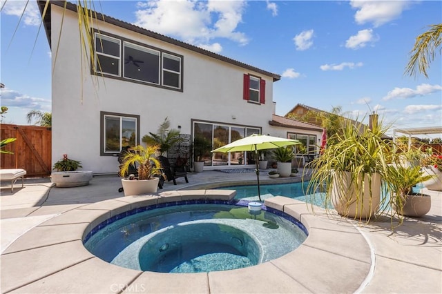 view of pool with a patio area, fence, and a pool with connected hot tub