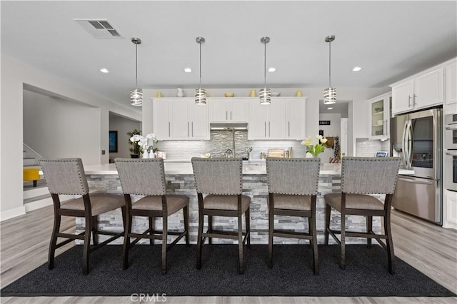 kitchen featuring visible vents, white cabinets, light wood-style floors, and stainless steel refrigerator with ice dispenser