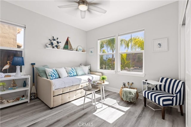 living room with baseboards, ceiling fan, and wood finished floors