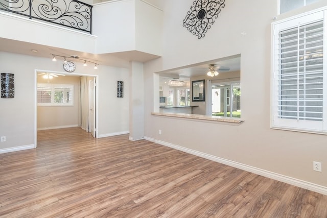 unfurnished living room featuring baseboards, ceiling fan, and wood finished floors