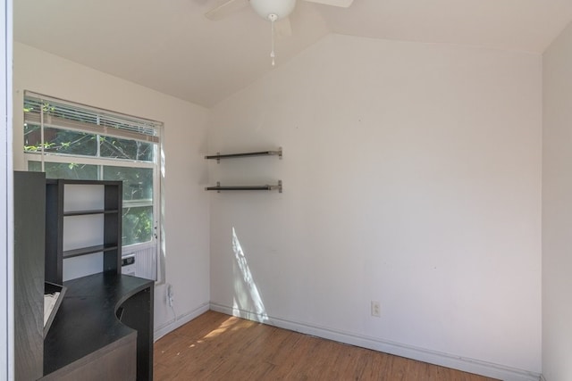 interior space with wood finished floors, a ceiling fan, baseboards, and vaulted ceiling