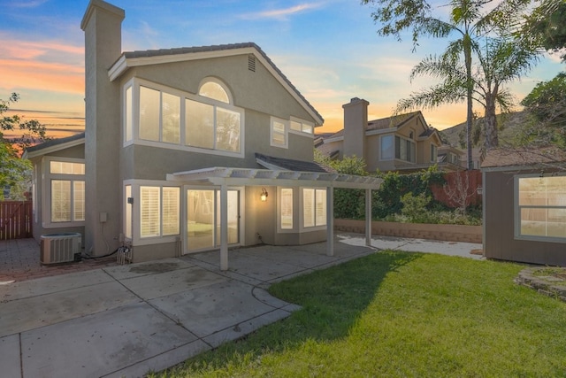 back of property at dusk featuring fence, a yard, a pergola, stucco siding, and central air condition unit