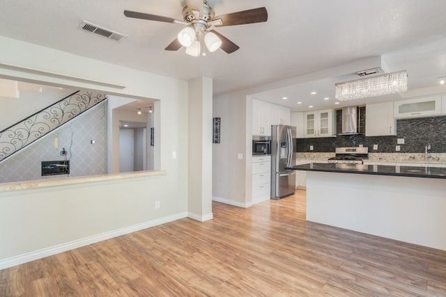 kitchen with visible vents, light wood finished floors, stainless steel appliances, white cabinetry, and wall chimney exhaust hood