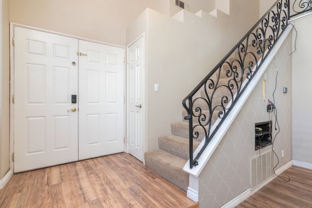 foyer with stairway, baseboards, visible vents, and wood finished floors