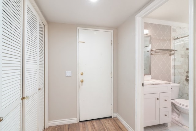 interior space featuring baseboards, toilet, tiled shower, wood finished floors, and vanity