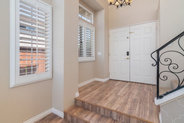 entrance foyer featuring a notable chandelier, stairway, baseboards, and wood finished floors