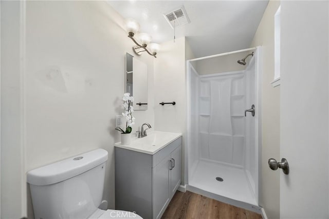 full bathroom with visible vents, toilet, wood finished floors, a shower stall, and vanity