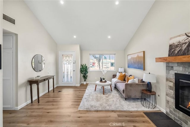 living area with visible vents, baseboards, wood finished floors, and a fireplace