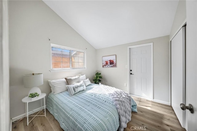 bedroom featuring a closet, baseboards, lofted ceiling, and wood finished floors