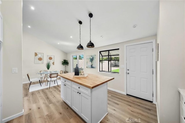 kitchen with light wood finished floors, butcher block countertops, pendant lighting, and white cabinetry