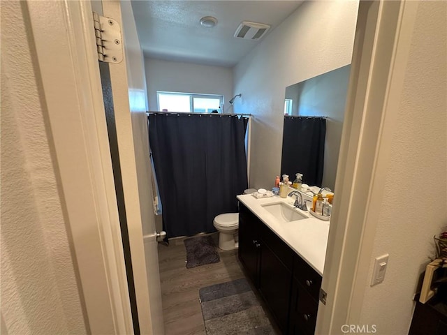 full bath with visible vents, curtained shower, toilet, wood finished floors, and vanity