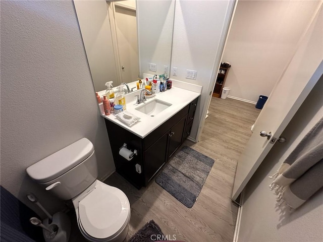 bathroom featuring toilet, wood finished floors, and vanity