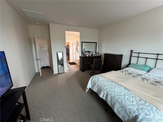 carpeted bedroom with visible vents and a walk in closet