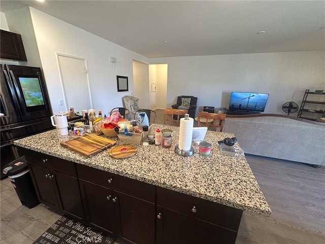 kitchen featuring light stone countertops, open floor plan, a center island, and light wood finished floors