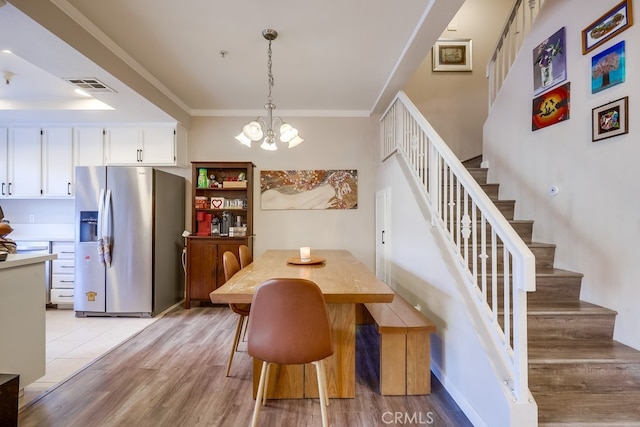 dining area with visible vents, ornamental molding, a chandelier, light wood-style floors, and stairway