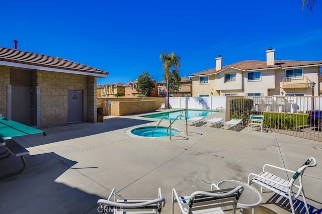 community pool with a patio, fence, a residential view, and a hot tub