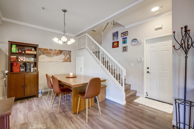 dining area with crown molding, a chandelier, wood finished floors, and stairs