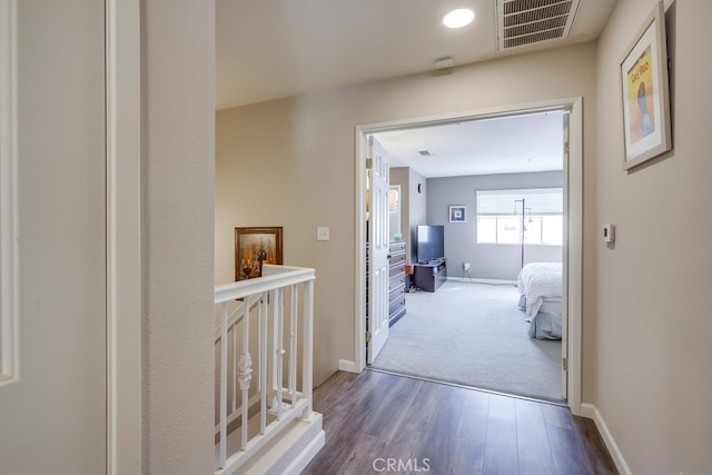 hallway with wood finished floors, baseboards, and visible vents
