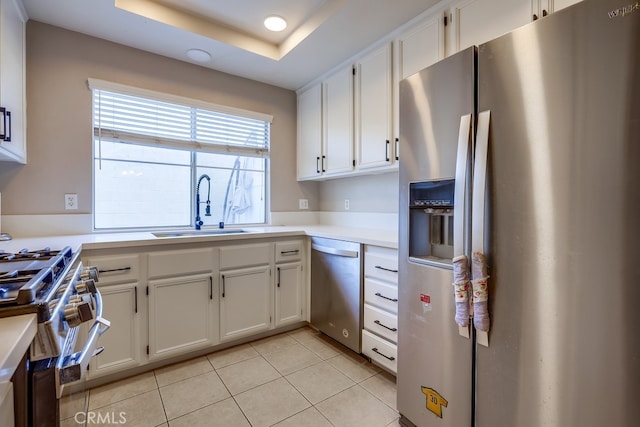 kitchen featuring light countertops, appliances with stainless steel finishes, a sink, and white cabinets
